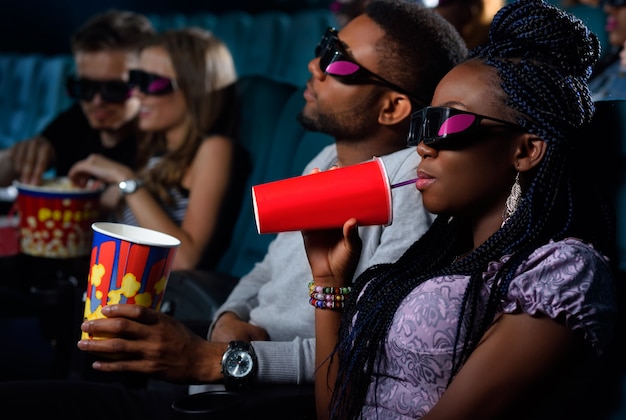 African woman enjoying her drink on a date with her man at the movie theatre