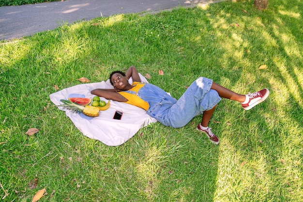 African woman having a picnic of fruits such as watermelon pineapple apples and banana