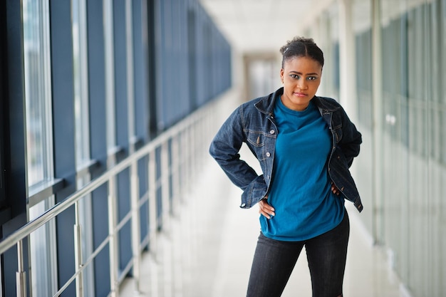 African woman in jeans jacket posed indoor.