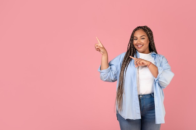 African Woman Pointing Fingers Aside At Copy Space Pink Background