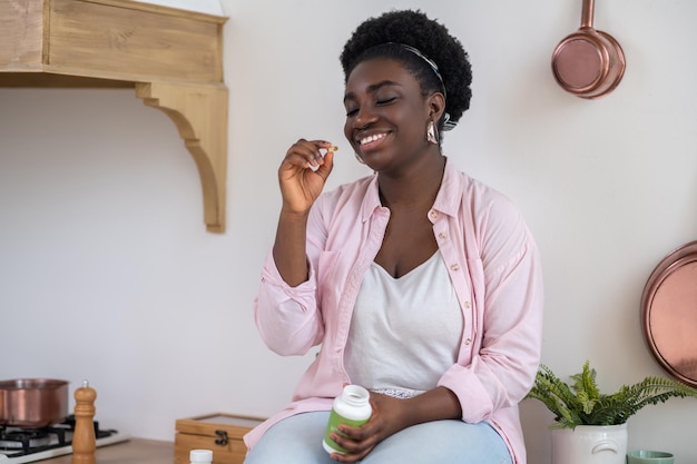 African woman sitting on the table with pills in hands