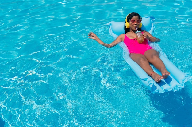 African Woman sunbathing drinking a juice in a swimming pool