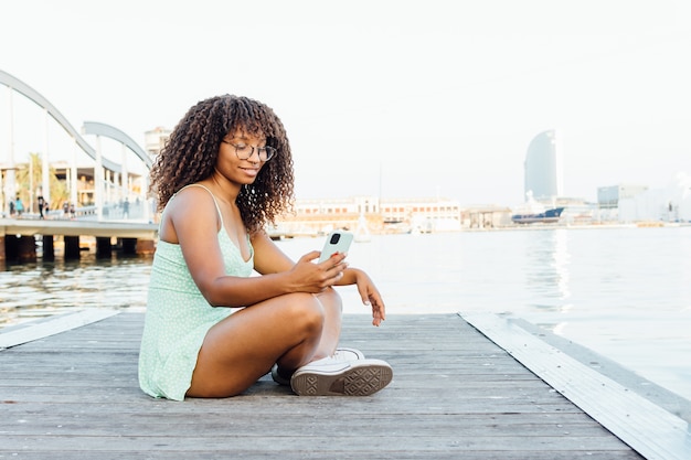 African woman using her smartphone by the sea