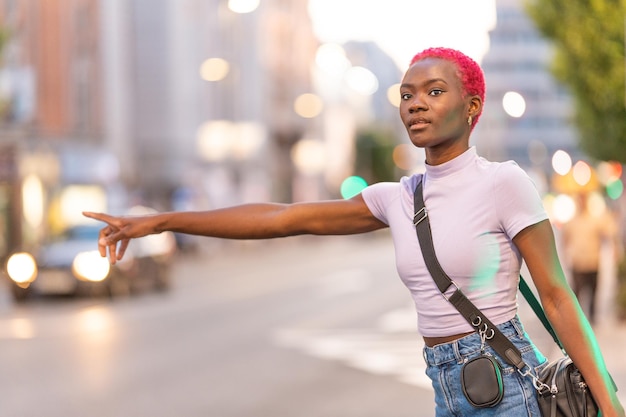 African woman with short pink hair hairstyle hailing a taxi