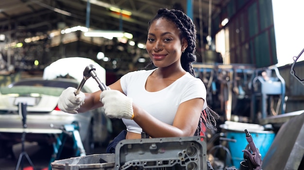 African young female car mechanic checking and fixing car engine at service car garage Black woman mechanic working in car service and maintenance workshop