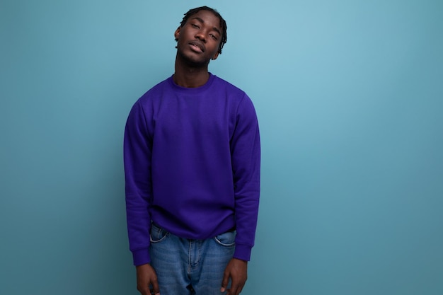 African young man with dreadlocks in a blue sweatshirt in the studio with copy space