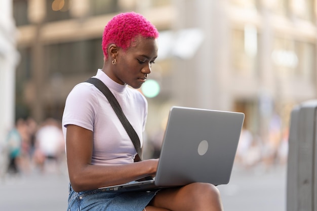 African young woman working with laptop on the street