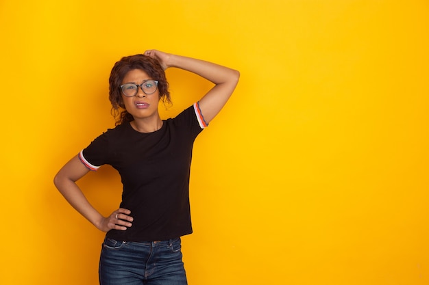 Africanamerican beautiful young womans portrait on yellow studio background emotional and expressive