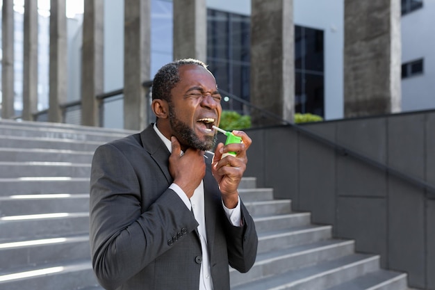 An africanamerican businessman is standing on the street near an office center and blowing an