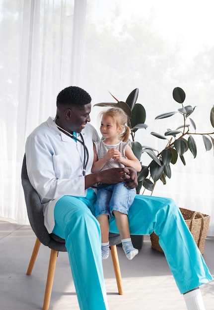 An AfricanAmerican doctor communicates with a little girl patient