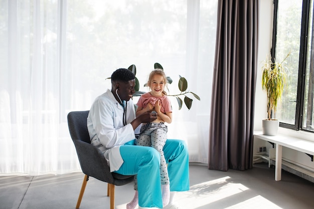 An AfricanAmerican doctor examines a child with a stethoscope