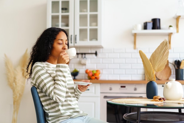 Africanamerican female drinking cup of tea and enjoying morning concept of slowliving lifestyle