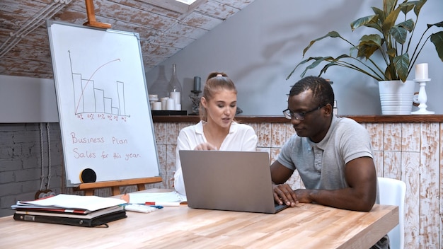 Africanamerican man and caucasian woman at the business meeting a board with graphics