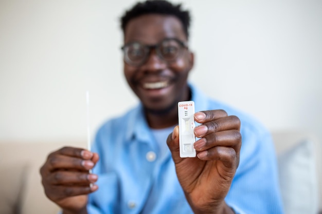 AfricanAmerican man holding a negative test device Happy young man showing his negative Coronavirus  Covid19 rapid test Coronavirus