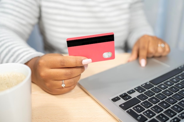 Africanamerican woman buying online on laptop at home