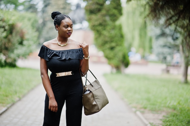 Africanwoman posed at street of city wear on black, with handbag