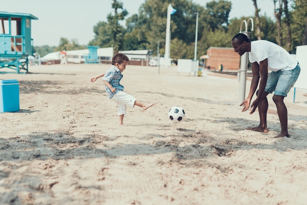 Afro-American Father and Son are Playing with Football Ball