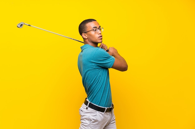 Afro American golfer player man over isolated yellow background