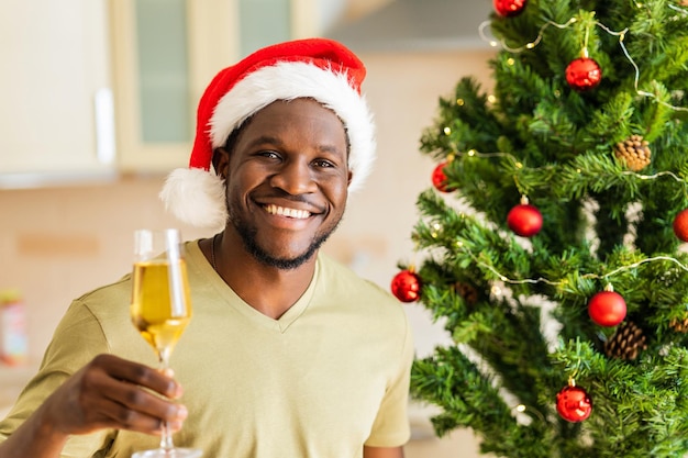 Afro american man raised a glass of champagne and makes a toast at home