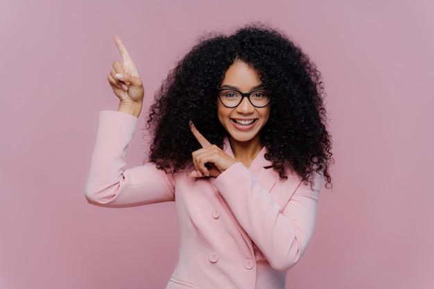 Afro American woman with dark bushy hairstyle, wears violet suit