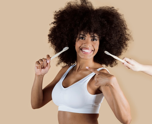 Afro American woman with toothbrush, cream cosmetics, spa beauty, beige background