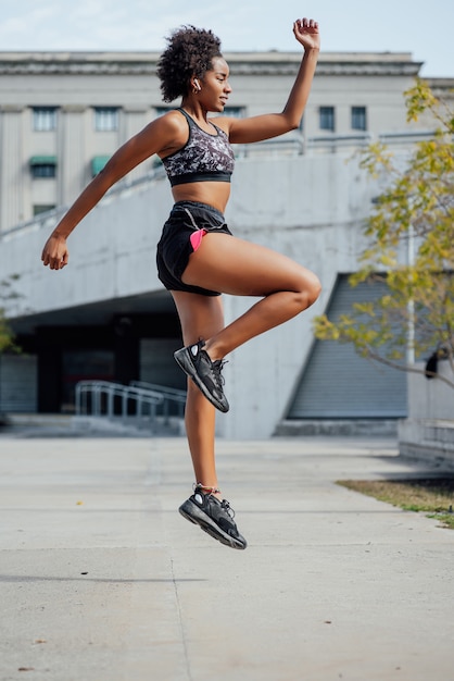 Afro athletic woman doing exercise outdoors on the street. Sport and healthy lifestyle concept.