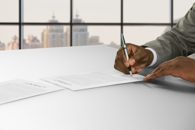 Afro businessman&amp;#39;s hand signs contract. Man signing contract in town. He agreed to the proposition. Good salary and nice perspective.