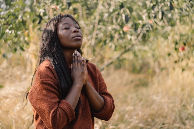 Afro Girl with closed eyes, praying outdoors