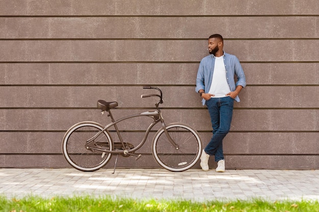 Photo afro man with stylish bicycle posing over grey urban wall