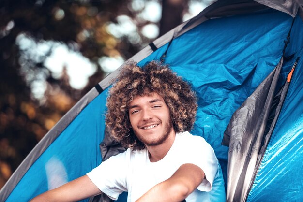 Photo an afro teenager is sitting in front of a mountain tent in the early morning