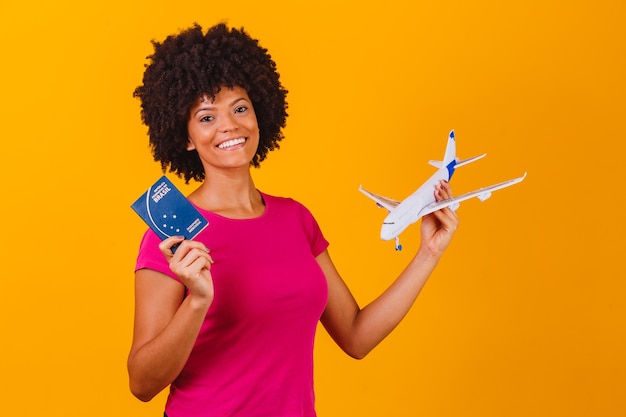 Afro woman holding a toy airplane and brazilian passport. Travel conceptafro woman holding a toy airplane and brazilian passport. Travel concept