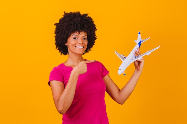 Afro woman holding a toy airplane. Travel concept