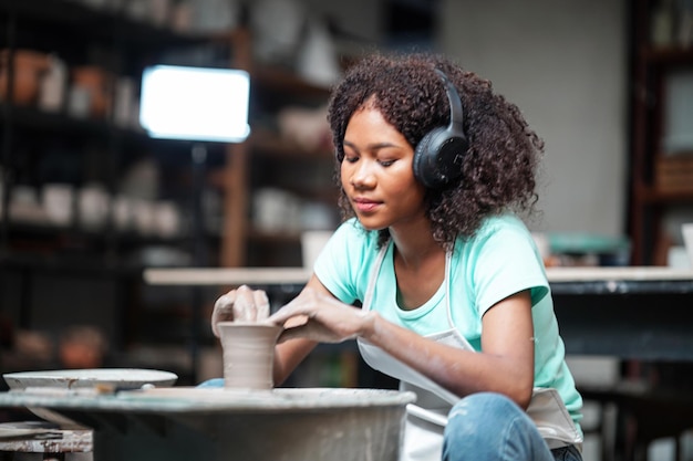 Afro Woman making pottery in workshop Shaping wet clay on pottery wheel