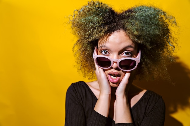 Afro woman surprised on yelloy background