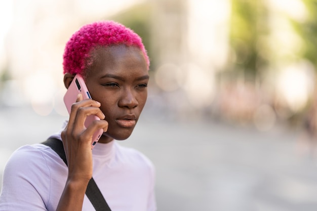 Afro woman with a distrustful expression talking on a mobile