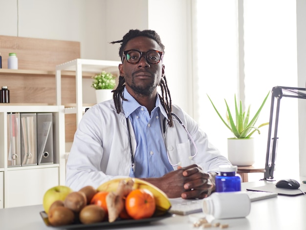 Afroamerican nutritionist looking at camera and showing healthy fruits in the consultation