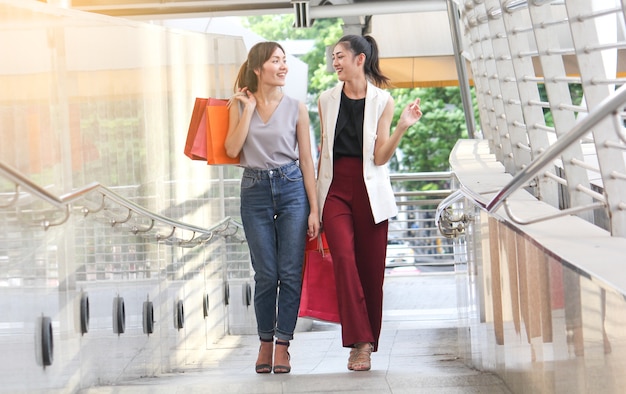 After day shopping. Close-up of two young woman carrying shopping bags while walking along the street