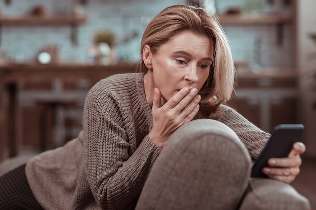 After seeing message. Dark-eyed concerned woman feeling emotional after seeing message from husband