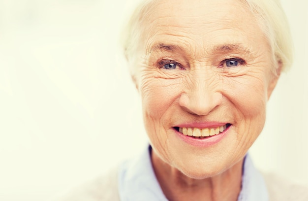 age and people concept - happy smiling senior woman face at home