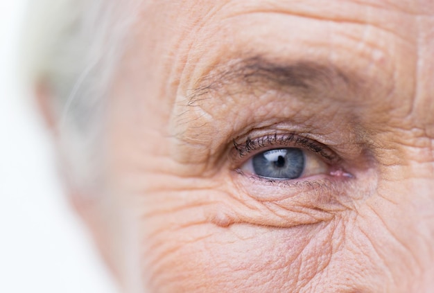 age, vision and old people concept - close up of senior woman face and eye