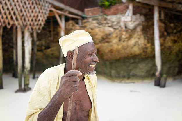 Aged african shepard walking on the beach holding stick