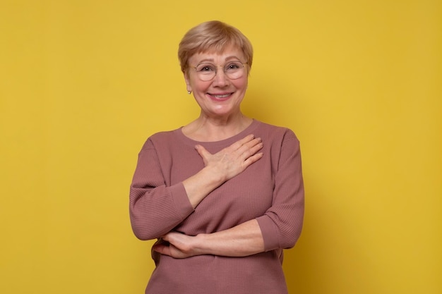 Aged caucasian lady with glasses posing to the camera smiling