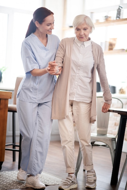 Aged woman making first steps after surgery on legs