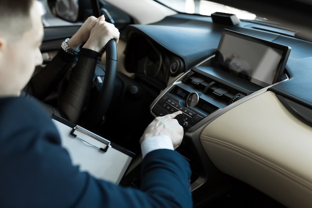 Agent and buyer girl inside a car in a car dealership. seller shows the car to the buyer.