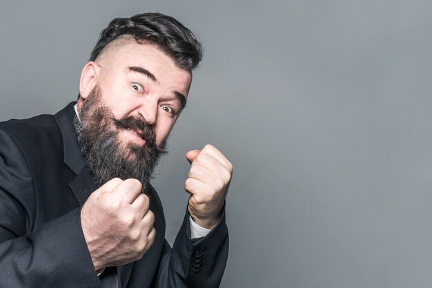 Aggressive adult bearded man in a suit showing fists Toned