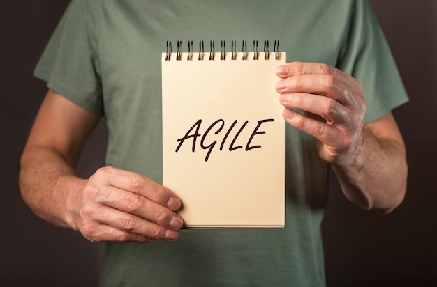 Agile word on notepad paper in male hands close up