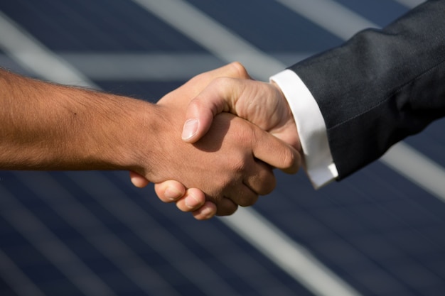 Agreeman handshake, solar panel on background.