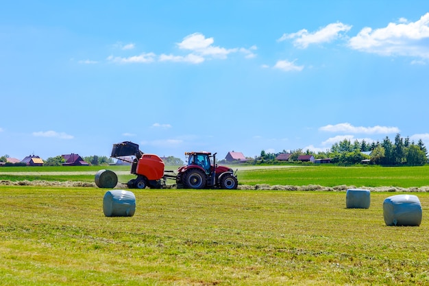 Agricultural baler that unloads a bale of hay while baling dry pasture grass for winter feeding.