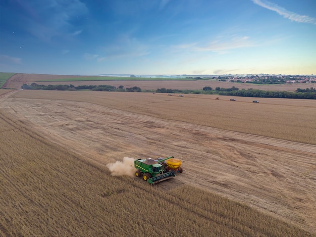 Agricultural tractor harvesting soybeans in the field.