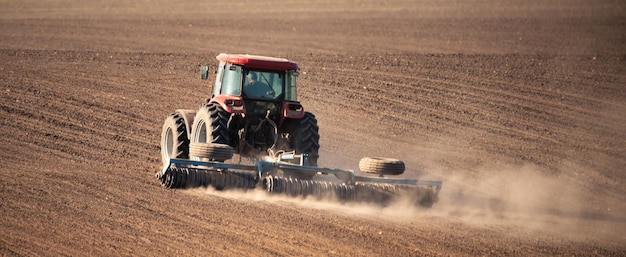 Agricultural tractor with cultivator attachment in motion